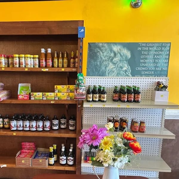 A store shelf filled with various sauces, spices, and other food products, with a motivational poster.