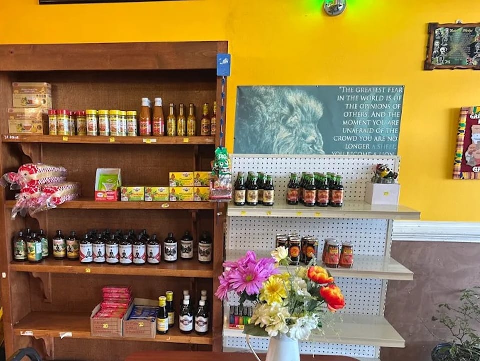 A store shelf filled with various sauces, spices, and other food products, with a motivational poster.